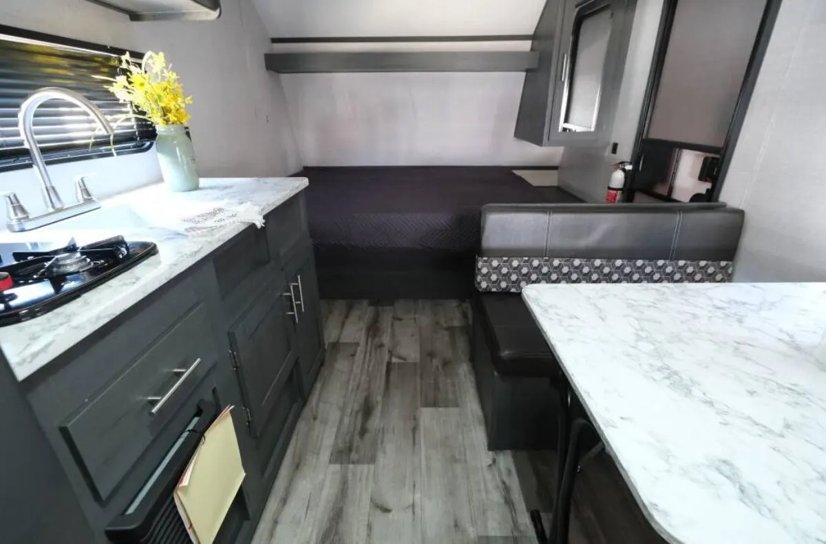 Interior view of the RV with a dinette, bedroom and a kitchen.