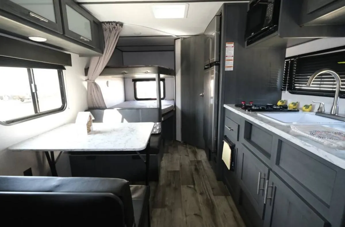 Interior view of the RV with a dinette, bedroom and a kitchen.