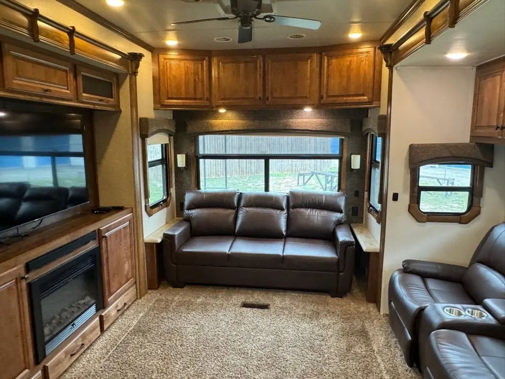 Living space with leather seats and overhead cabinets. 