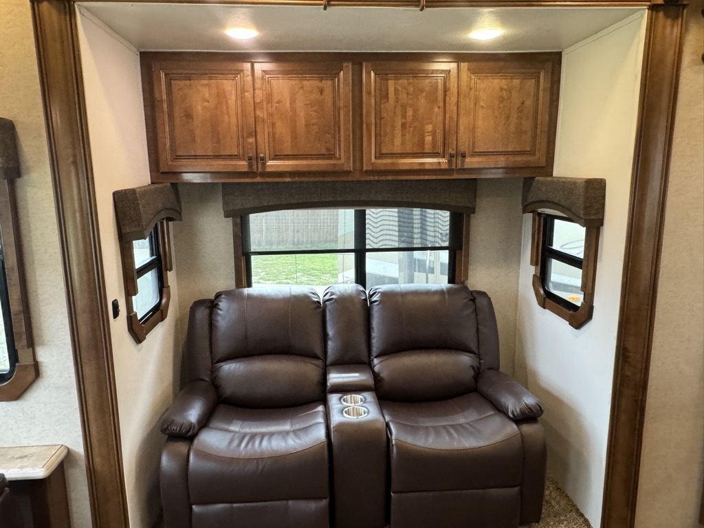 Living space with leather seats and overhead cabinets. 