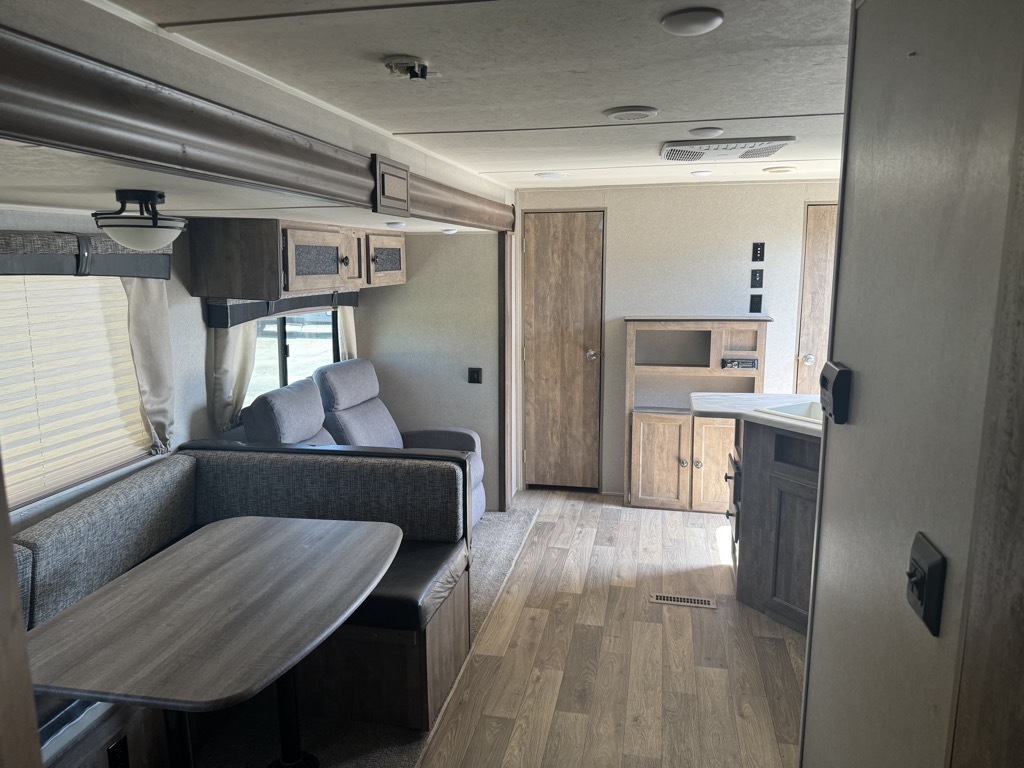 Interior view of the RV with a dinette, living space and a kitchen.