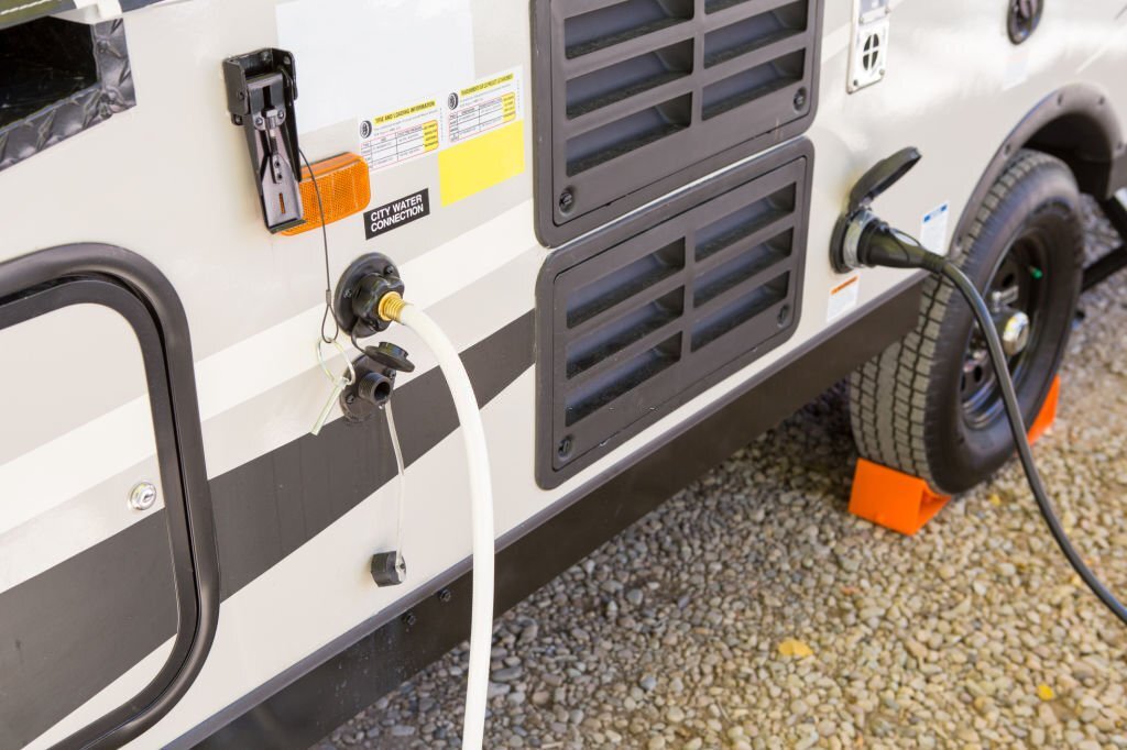 Close-up of an RV showing the city water and power connections.