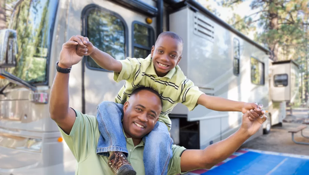 A father with his son posing in front of an RV