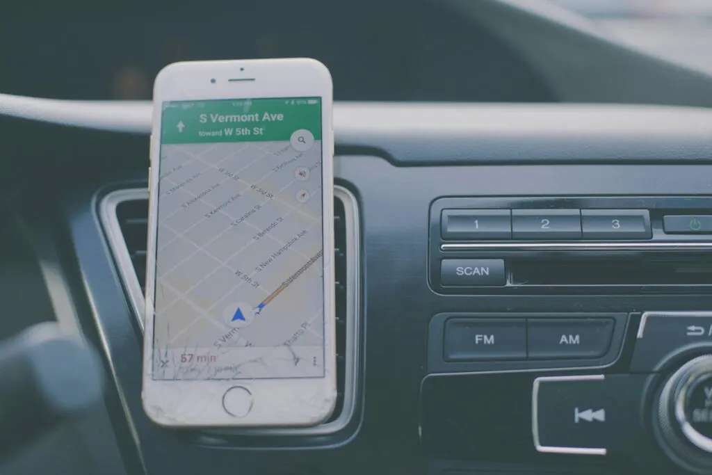 A smartphone displaying a map on Google Maps, mounted on the dashboard of a car.