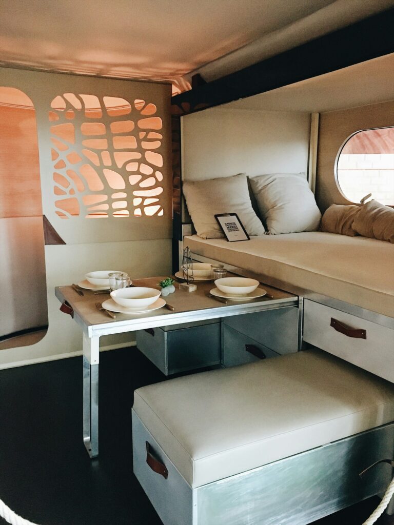  Interior of an RV with beige seats, grey wooden cabinets, and a dining table