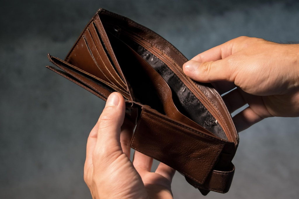 A close-up of a pair of hands holding an empty, open brown wallet.