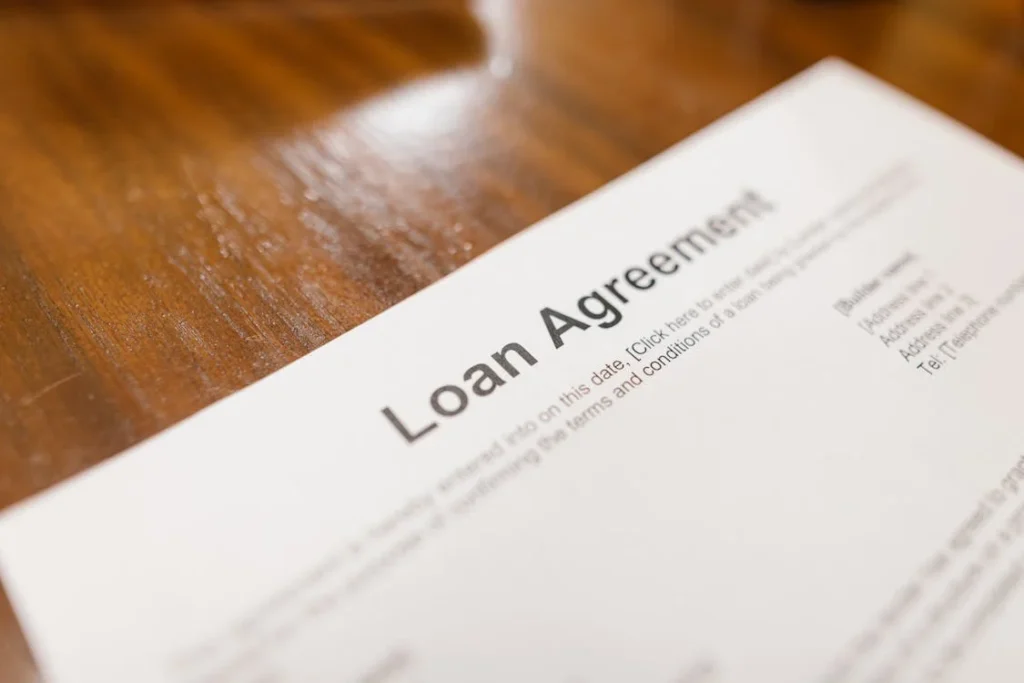 A close-up of a loan agreement document on a wooden table.