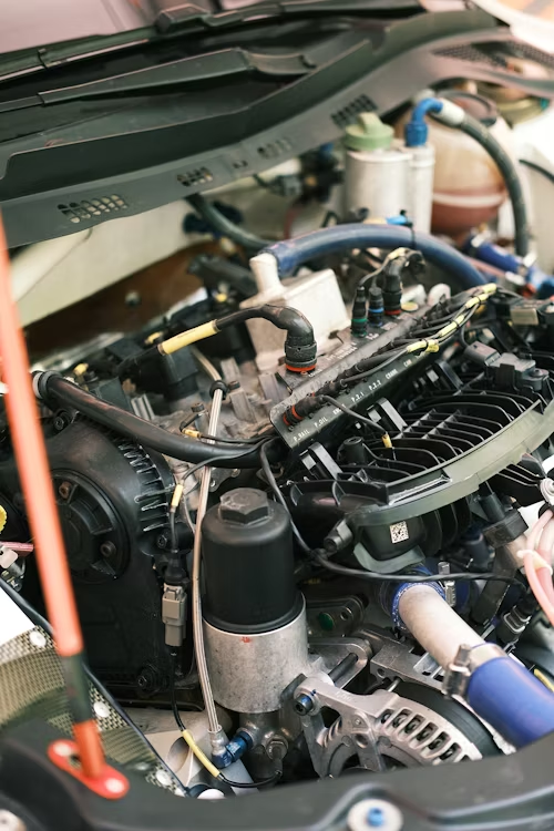 Close-up of a car engine with multiple components and cables visible.