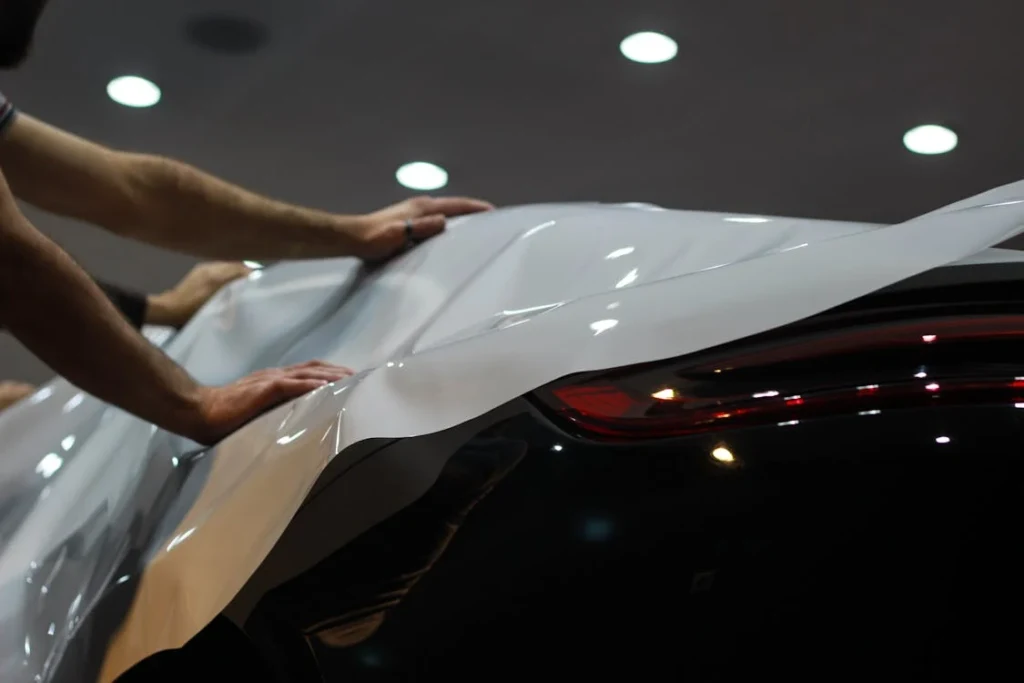  Close-up of two people applying a vehicle wrap on the rear of a car.