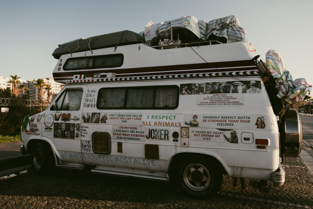 A heavily decorated camper with various stickers and writings parked in an urban area.