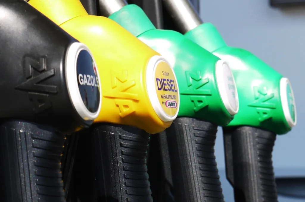 Close-up of fuel pump nozzles in different colors labeled GAZOLE, Super DIESEL, and other types of fuel.