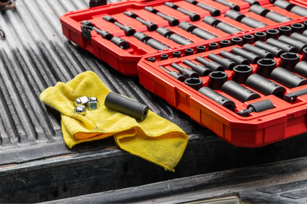 A toolset with various sockets on a workbench along with a yellow cloth and some bolts.