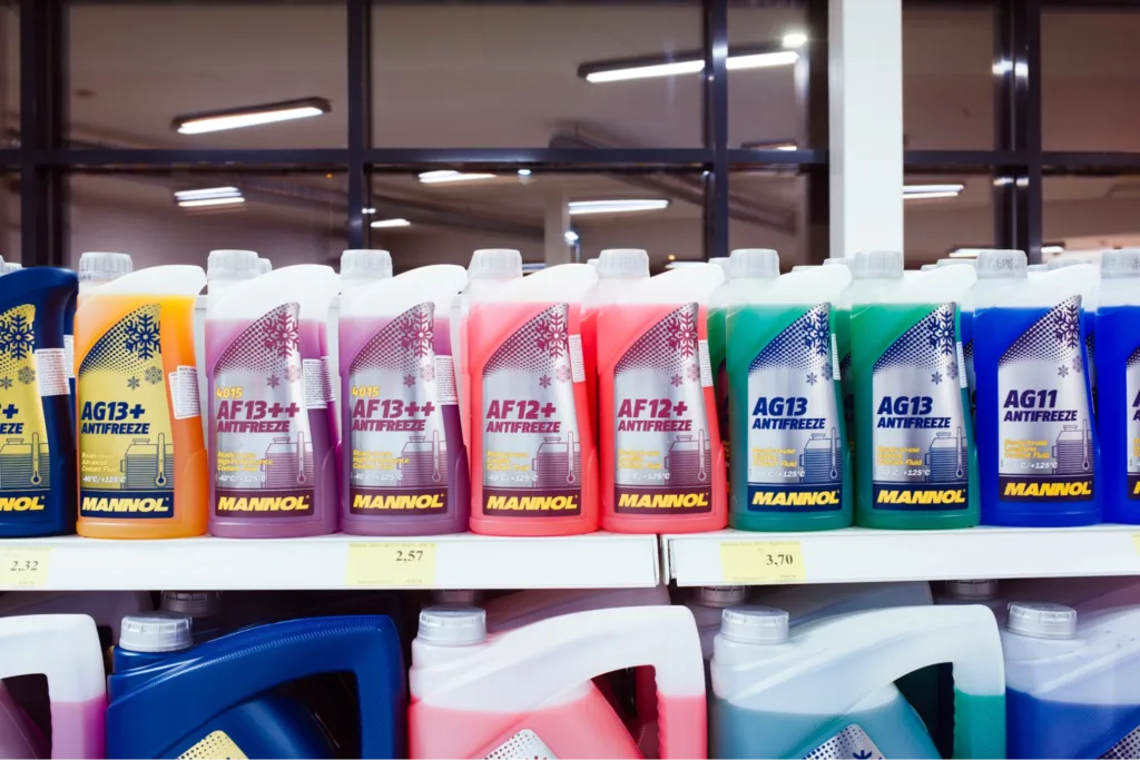 A store shelf lined with various colorful bottles of antifreeze/coolant.