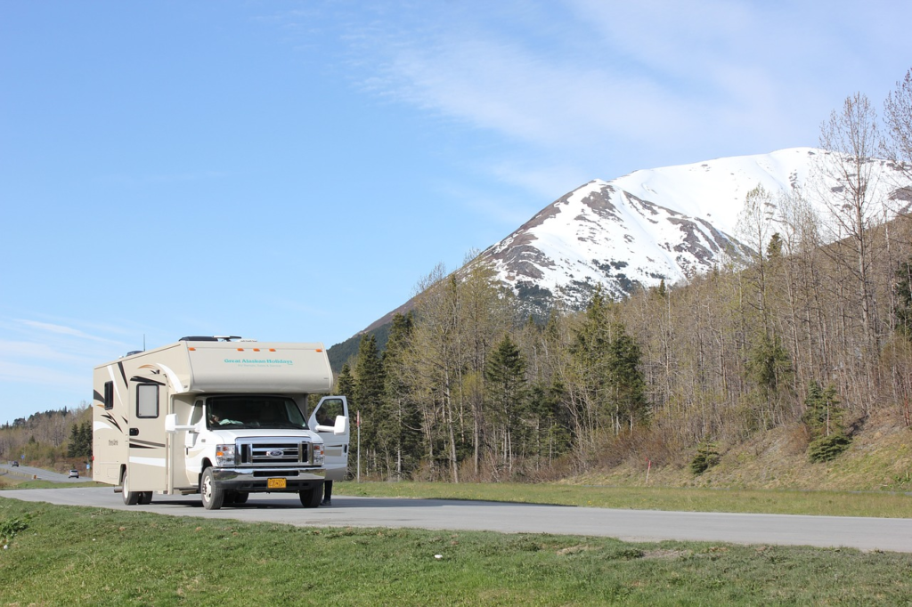 A motorhome parked on the roadside with a snowy mountain in the background.