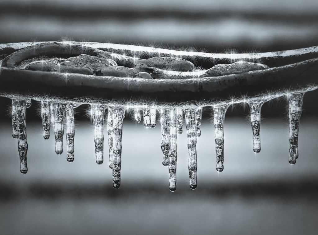 Close-up of icicles hanging from a metal object, sparkling in the light.