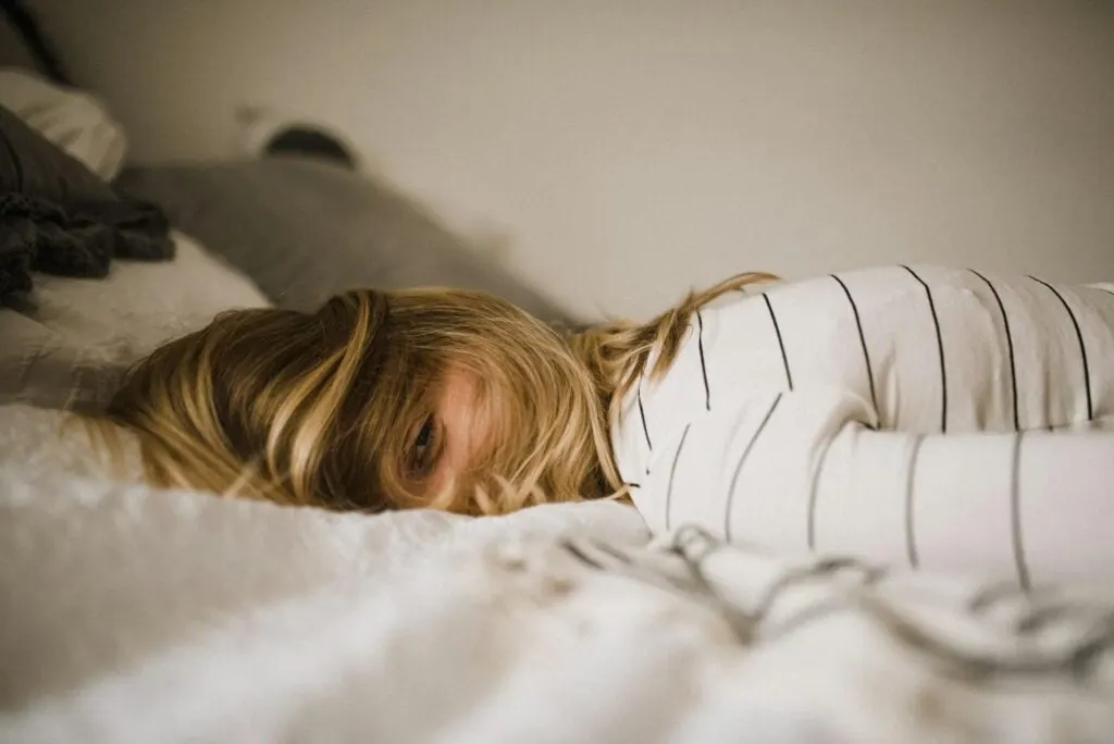 A woman lying face down on a bed, partially covered with their hair.