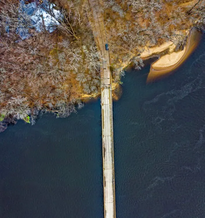 A bridge road across the body of water surrounded by a winter forest