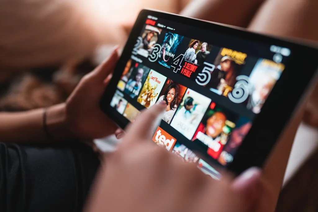 A person holding a tablet displaying a streaming service interface.