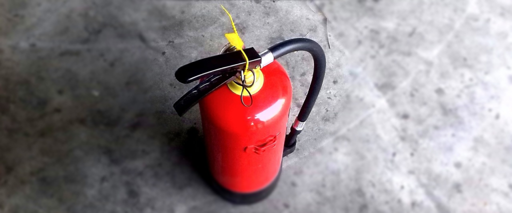 A red fire extinguisher placed on a concrete surface.