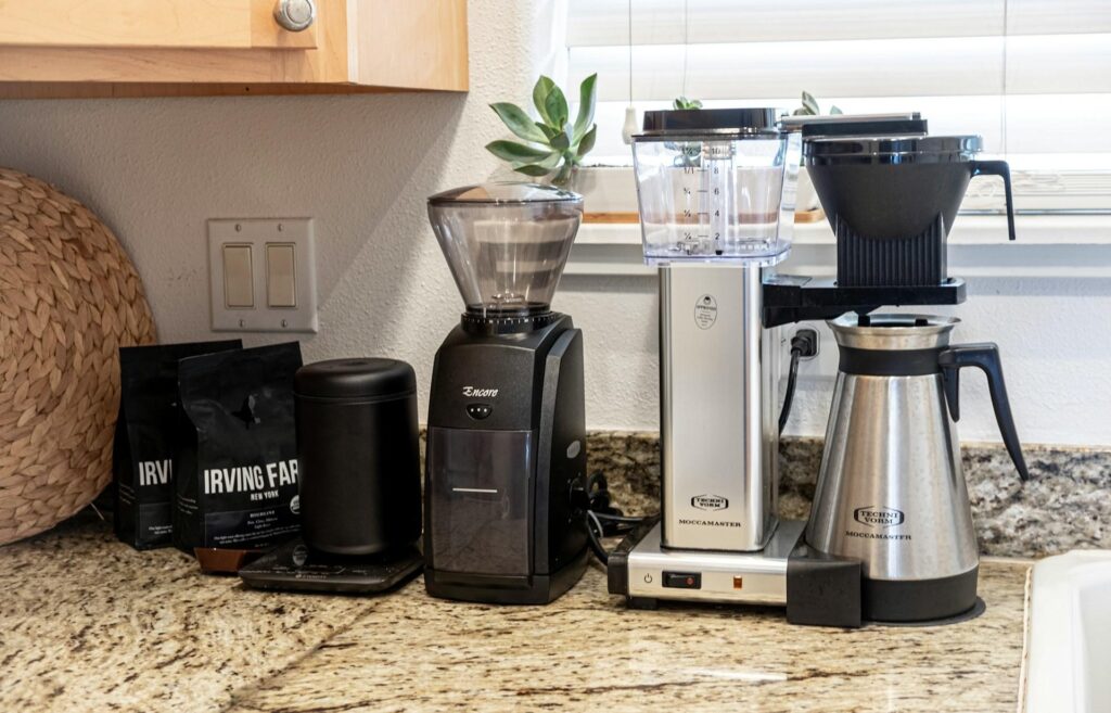  A coffee station on a kitchen counter, featuring a coffee grinder, coffee maker, coffee beans, and a coffee scale.