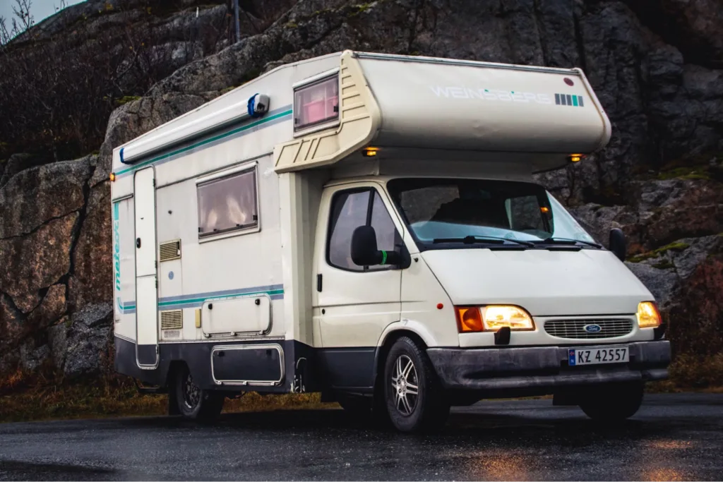 A "Weinsberg" campervan parked on a roadside with rocky surroundings.