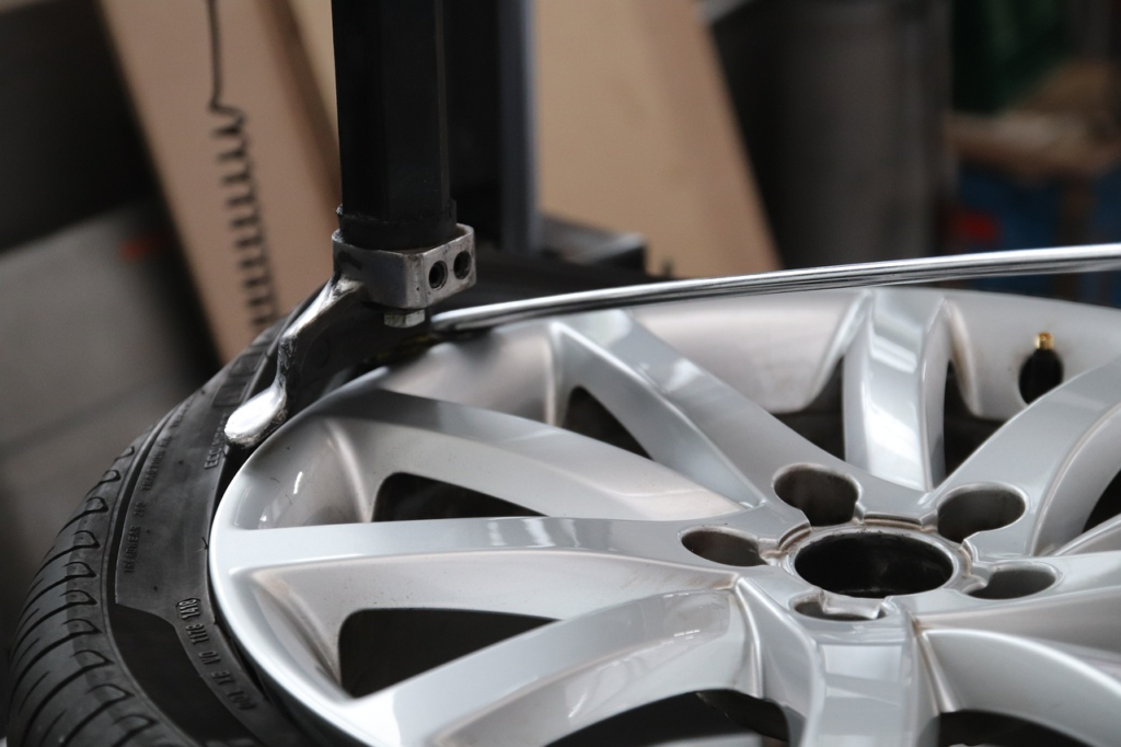 Close-up of a tire being mounted onto a silver rim at an auto shop.