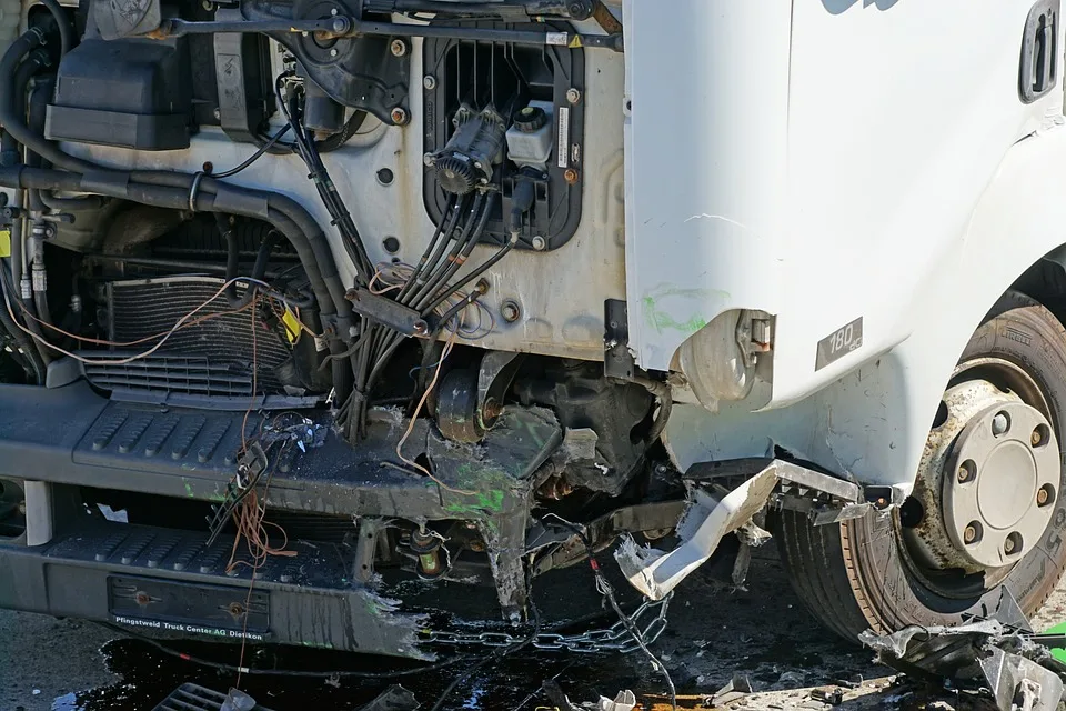 The front part of a damaged white truck with visible engine components.