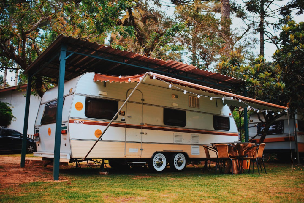 A campervan with an extended awning and string lights illuminating a cozy setup with a table and chairs outside.