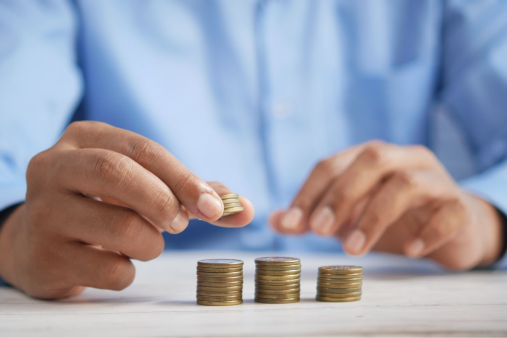 A person stacking coins into piles on a table, symbolizing savings or financial planning.