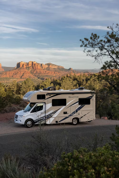 A campervan parked on a road with scenic red rocks visible in the background.