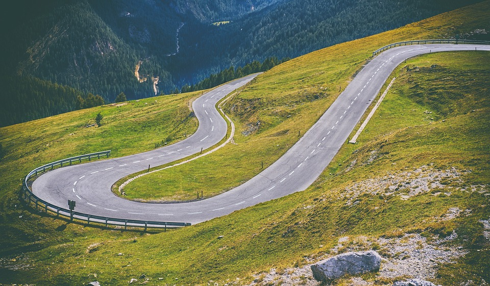 A winding road cutting through a hilly grassy landscape.