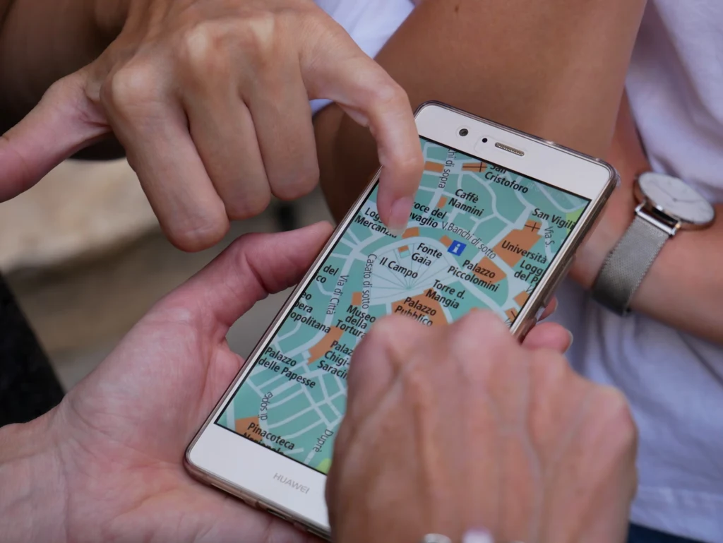 Multiple people pointing at a map displayed on a smartphone.