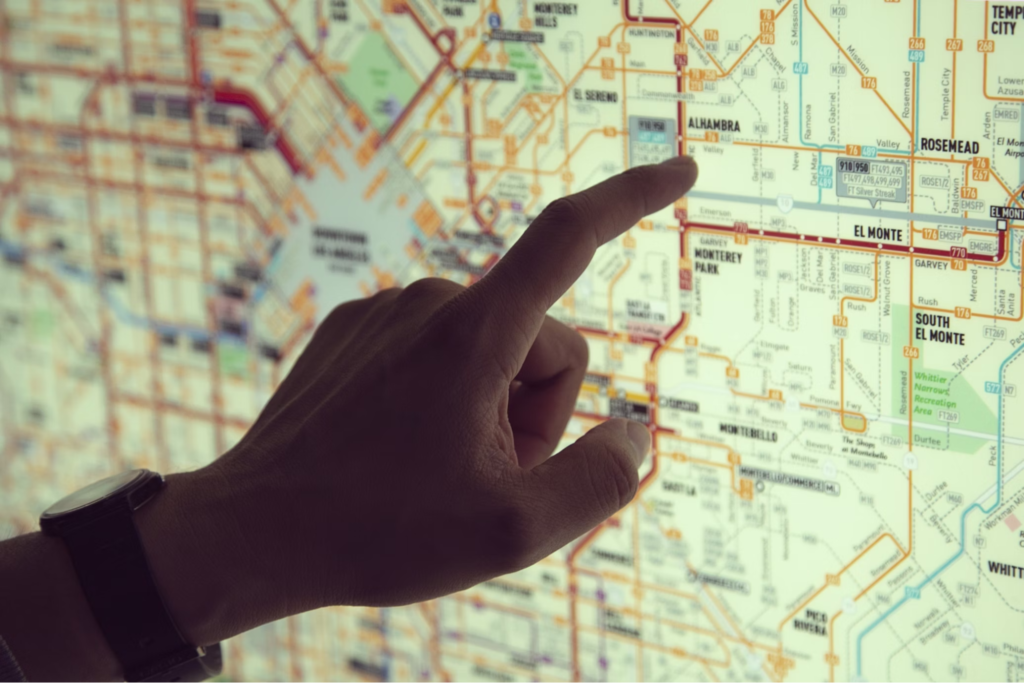 A hand pointing at a detailed city map displayed on a screen or paper.