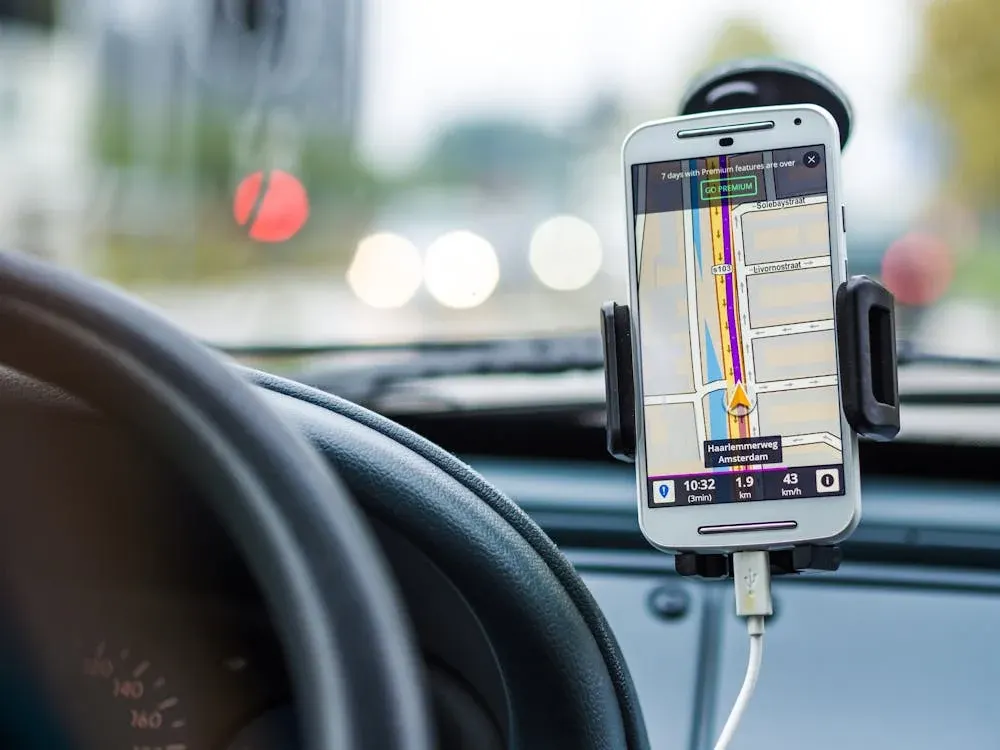 A smartphone mounted on a car dashboard, displaying navigation directions on its screen.