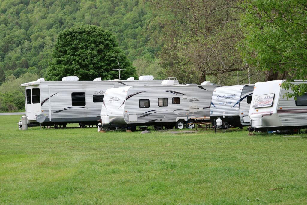 Several caravans parked on a grassy area with trees in the background.