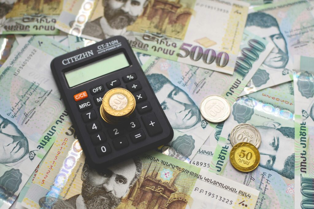 A workspace with a calculator, stacks of money and coins.