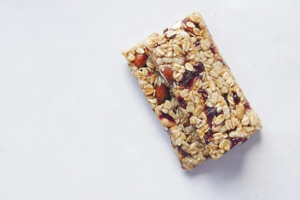 Two granola bars with oats, nuts, and dried fruit on a white background.