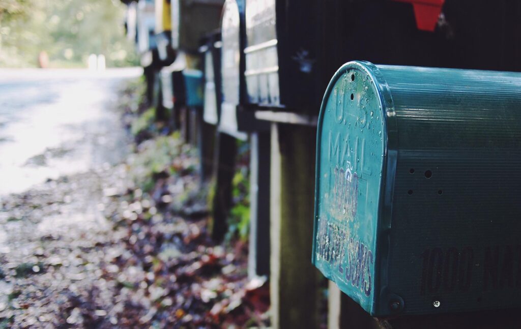 A close-up of weathered mailboxes lined up along a rural road.