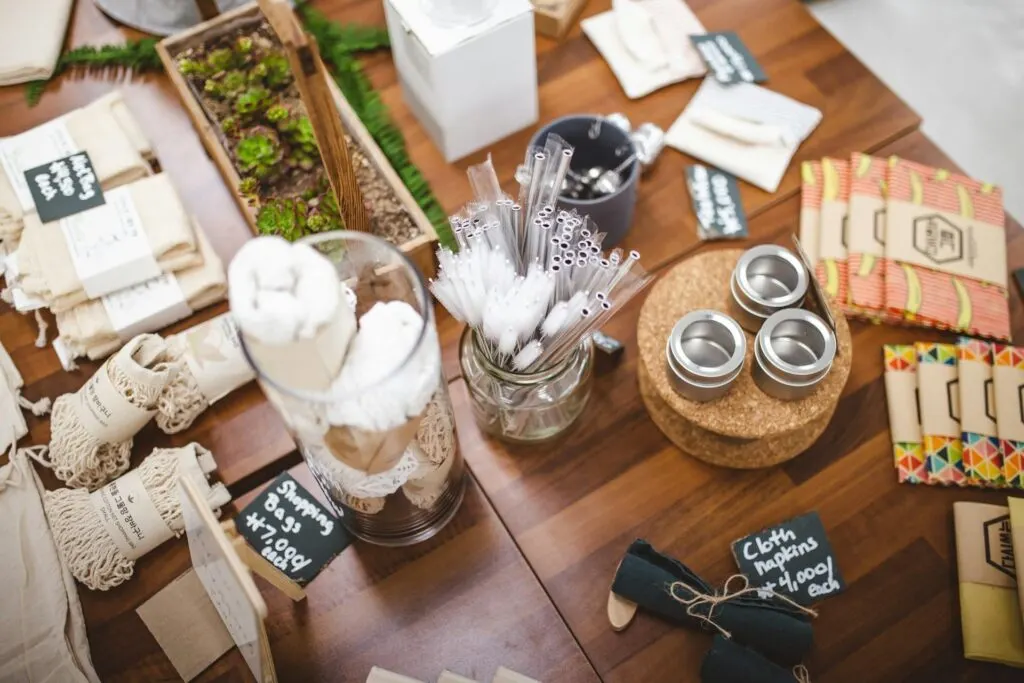 A table displaying various eco-friendly and reusable goods, including cloth napkins, straws, and shopping bags, as part of a zero-waste lifestyle setup.