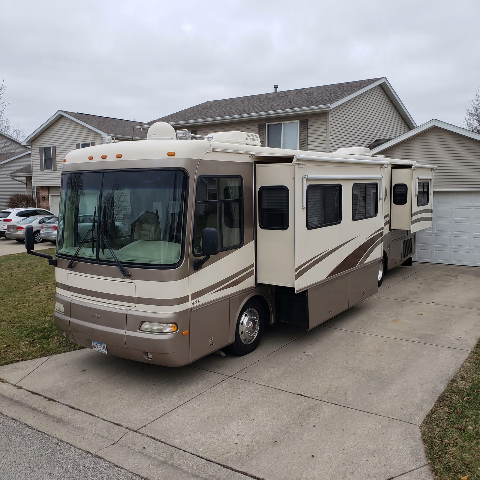 Forty-foot Class A diesel motorhome parked at an RV resort site with slide-outs extended and a patio mat.