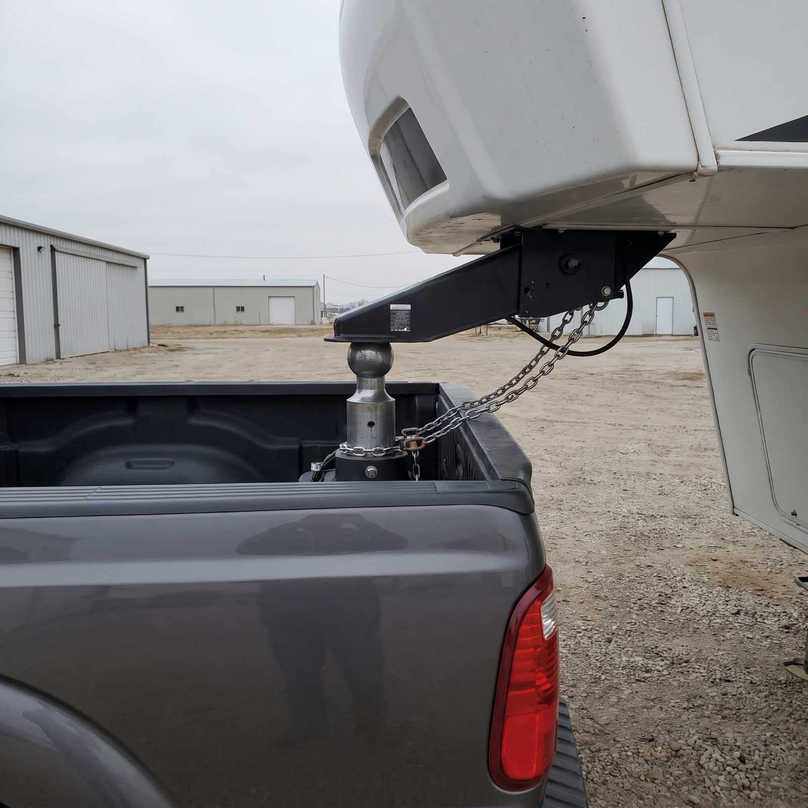 Fifth wheel RV interior with a diesel pickup hitched outside the rear window and a road atlas on the dinette table.